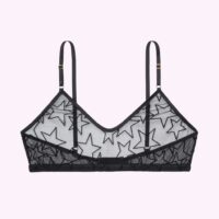 Flat lay of the Le Petit Trou Audre bralette. The bra is black and sheer, with velvet stars outlined flocked onto the material. The bralette is a sporty style with no darts and a scoop neck.