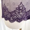 pictured on a dress form mannequin: close up of the bottom lace edge of the only hearts halter so fine lace bodysuit teddy in purple.