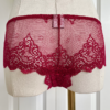back view of a mannequin posed with red lingerie. the mannequin wears the only hearts so fine lace coucou culotte brief. the mannequin is in front of a white door.