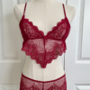 a mannequin posed with red lingerie. the mannequin wears the only hearts so fine lace coucou peek-a-boo bralette and the matching coucou culotte brief. the mannequin is in front of a white door.