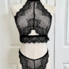 mannequin posed with black lingerie. mannequin wearing the only hearts so fine lace halter cami and matching lace thong panty. the mannequin is standing in front of a white door.