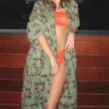 a model leans against a wall on a balcony with a sunset in the background. model wears an orange lace bandeau bra and orange lace briefs. On top the model wears the only hearts luv island cotton kimono robe in moss green with a tropical print.