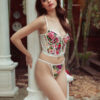a woman leans against a column wearing lingerie. model wears the kilo brava floral embroidered underwire bustier and g-string panty.