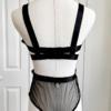back view of a mannequin wearing the kilo brava black embroidered lace underwire bodysuit. the mannequin is in front of white doors.