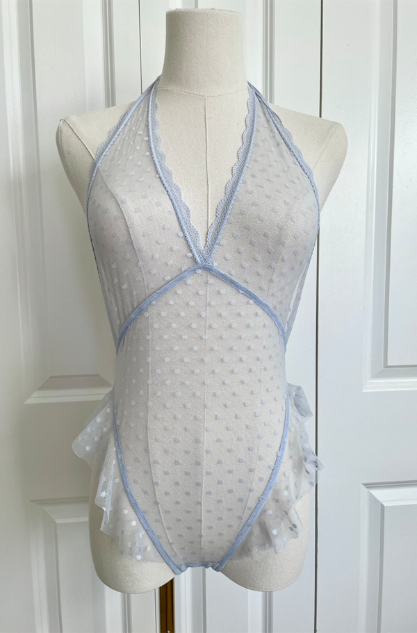 front view of a mannequin wearing the only hearts bettie teddy in crystal blue. It's a light blue sheer one piece in a polka dotted pattern. The mannequin is in front of a white door.