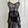 front view of a mannequin dressed with the only hearts coucou lola moonchild dress. It's a sheer black lingerie slip dress with a polka dot pattern, three ties at the bust, center front, and waist, and long ruffled skirt. Under the dress the mannequin has on sheer black underwear in the same dotted pattern.