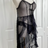 side view of a mannequin dressed with the only hearts coucou lola moonchild dress. It's a sheer black lingerie slip dress with a polka dot pattern, three ties at the bust, center front, and waist, and long ruffled skirt.