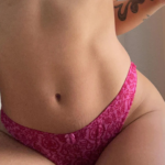 close up image of a model sitting, wearing the Only Hearts Message in a bottle basic thong - in 'wild rose' pink and red floral print