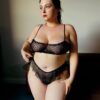 a model poses wearing the only hearts coucou lola joey bralette in black and matching flutter panties