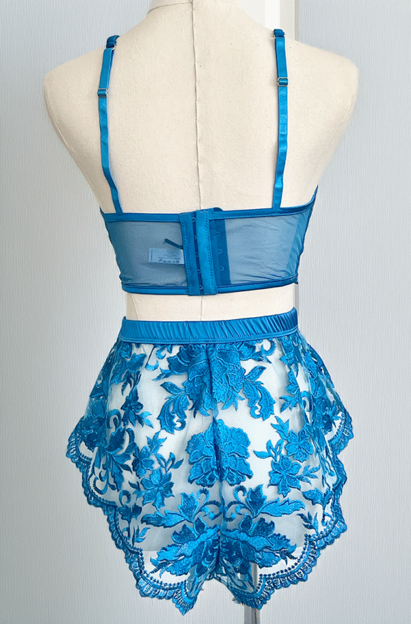 back view of kilo brava embroidered lace longline bralette and tap shorts in Hawaiian blue. Bra and shorts pictured on a mannequin in front of a gray backdrop